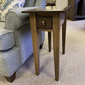 Wooden side table with small drawer beside sofa.