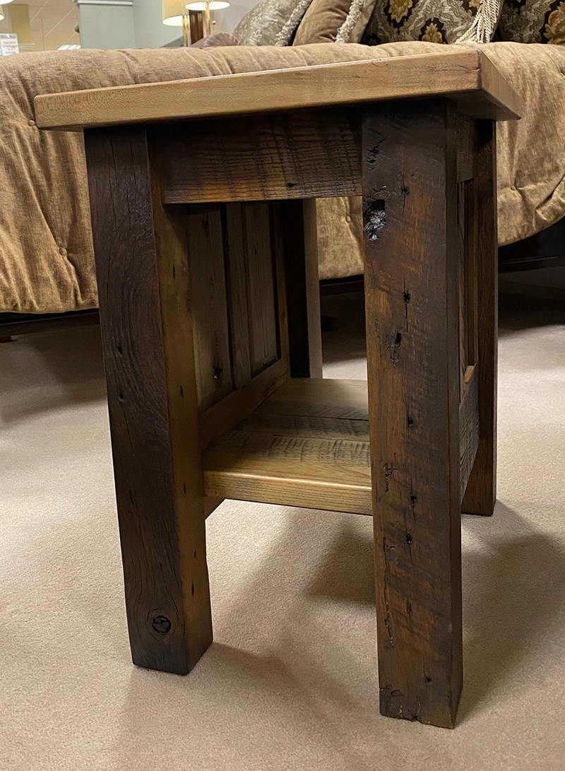 Rustic wooden stool beside a bed.