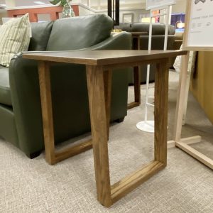 Wooden side table next to green sofa in store.