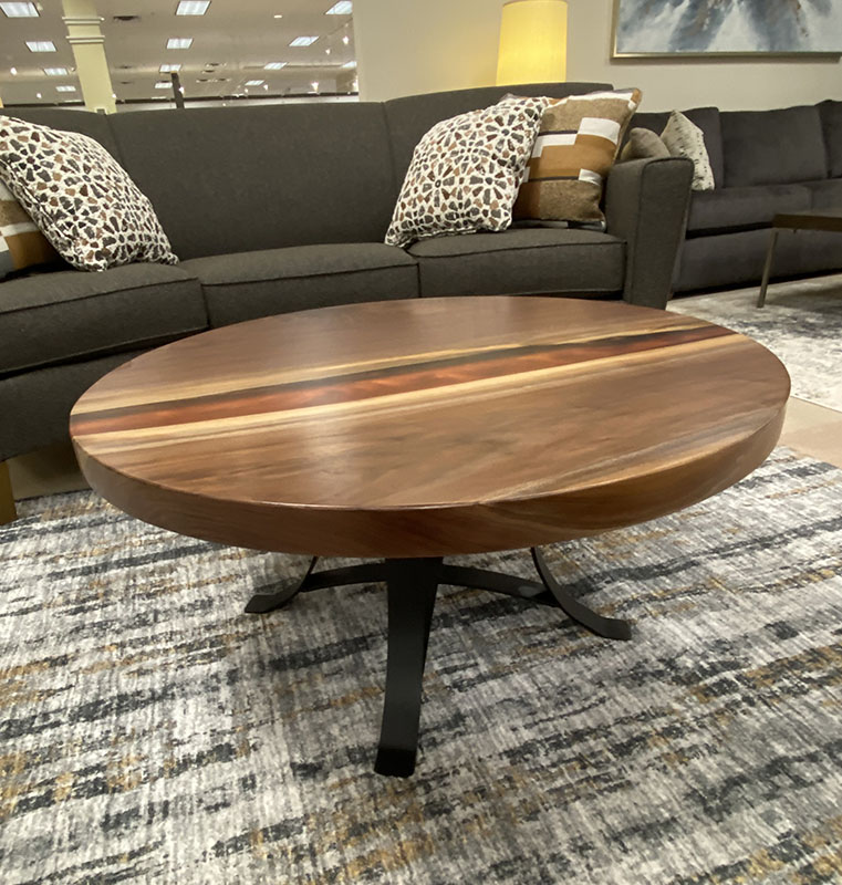 Round wooden coffee table in living room setup.