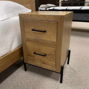 Wooden nightstand with two drawers beside bed.