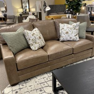 Comfortable brown leather sofa with decorative pillows.