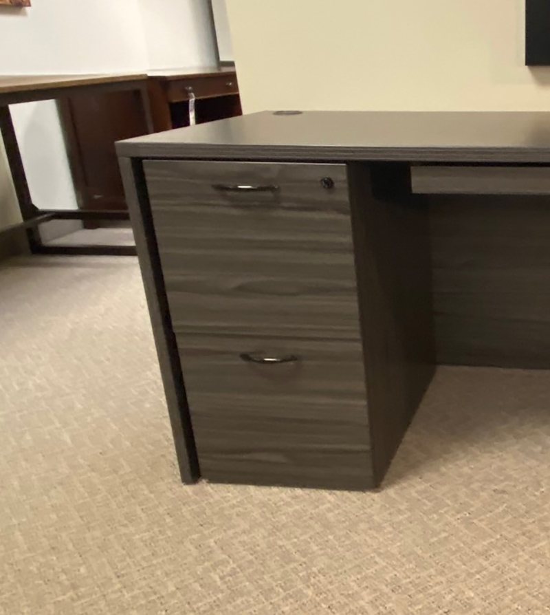 Dark wood office desk with drawers on carpet.