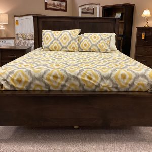 Wooden bed with patterned bedding in furniture store.