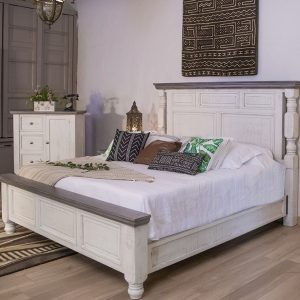 Rustic bedroom with white furniture and patterned pillows.